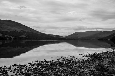 Scenic view of lake by mountains against sky