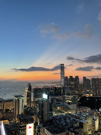 Illuminated buildings against sky during sunset in city