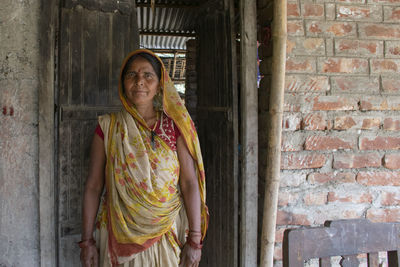 Portrait of indian woman wearing saree standing in front of door