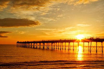 Pier over sea against sky during sunset