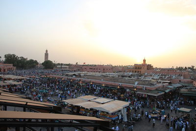 People in city against clear sky during sunset