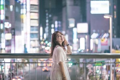 Woman standing against railing in city