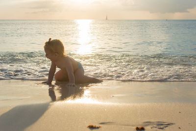 Boy on beach against sky during sunset