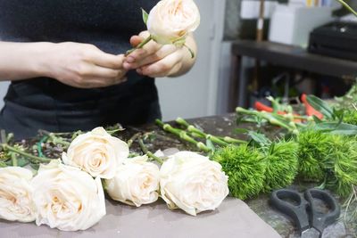 Midsection of florist with white roses at table