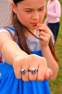 Cute girl showing skull rings on grassy field