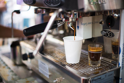 Coffee pouring in disposable cup from coffee maker in cafe