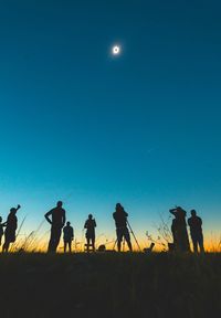 Low angle view of silhouette people against moon at night