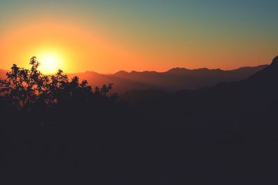 Scenic view of silhouette mountains against orange sky