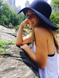 Side view of smiling young woman wearing hat