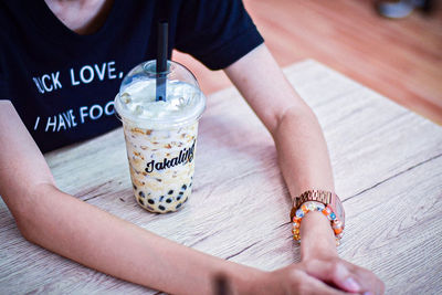 Close-up of hand holding drink on table