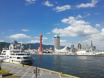 Sea by modern buildings against sky in city