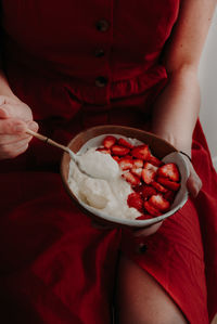 Midsection of woman eating dessert while sitting at home