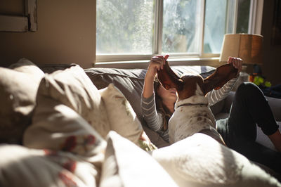 Low section of friends resting on bed at home