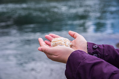 Close-up of man holding rock against lake