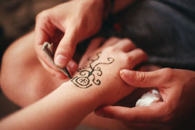 Cropped image of hands applying henna to person