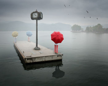 People standing on built structure at lake