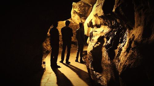 Silhouette friends standing in illuminated borra caves