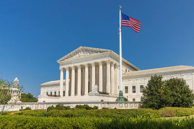 Low angle view of flags against clear blue sky