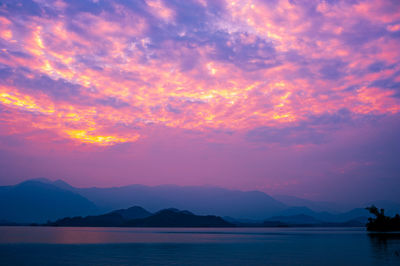 Scenic view of sea against dramatic sky during sunset