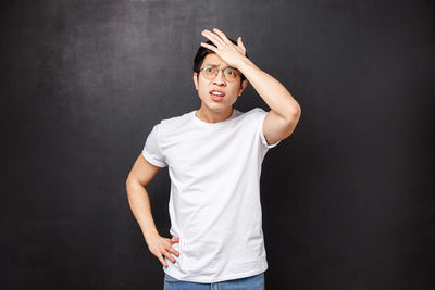 Worried man with head in hand against black background