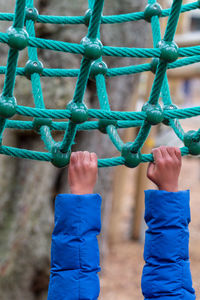 Cropped hands of child hanging on rope