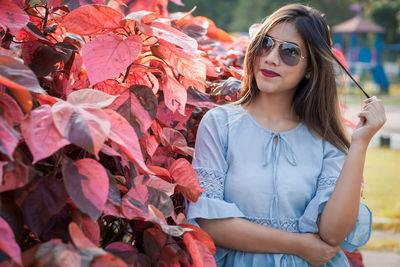 Young woman wearing sunglasses standing outdoors during autumn