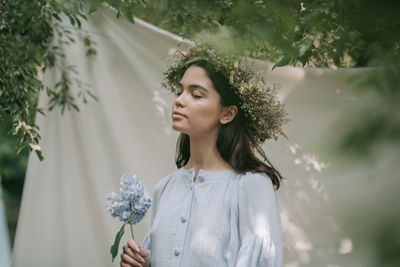 Portrait of beautiful woman standing by flower plants