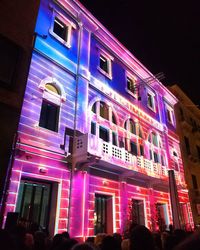 Low angle view of people on illuminated building at night