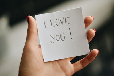 Close-up of hand holding paper with love text