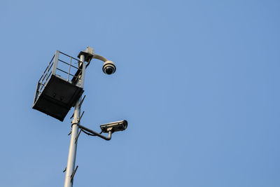 Low angle view of telephone pole against clear blue sky