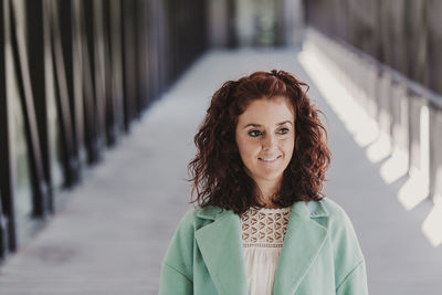 Portrait of smiling young woman standing against railing