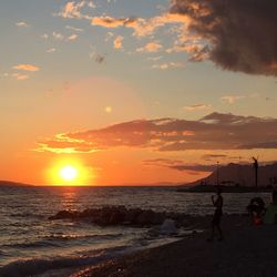 Silhouette people on beach against sky during sunset