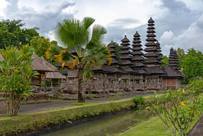 Built structure by trees and building against sky