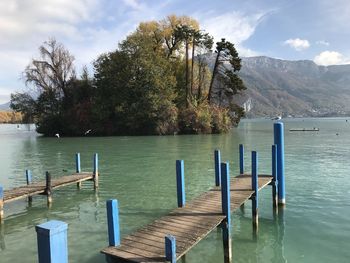 Wooden posts in lake against sky