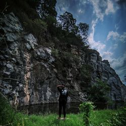 Rear view of man standing on rock against sky