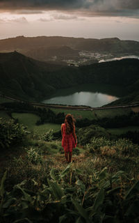 Rear view of woman standing on mountain against sky