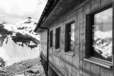 Abandoned building by snow covered mountains against sky