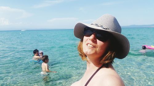 Portrait of smiling woman with family in sea against sky