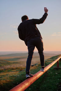 Low section of man standing on pier against sky during sunset
