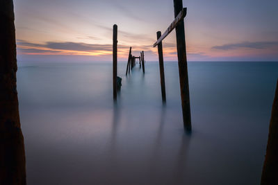 Broken pier on sea during sunset