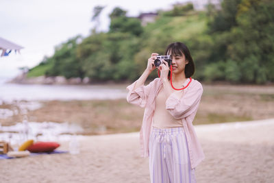 Woman photographing while standing at beach