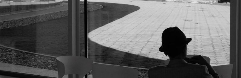 Rear view of woman sitting on railing