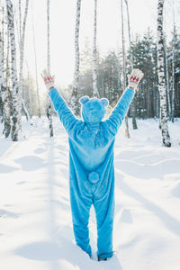 Rear view of mid adult man standing on snow covered field in forest