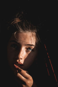 Close-up portrait of girl against black background
