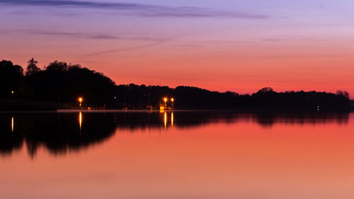 Reflection of trees in water at sunset