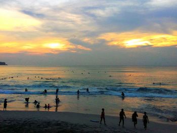 Silhouette people on beach against sky during sunset