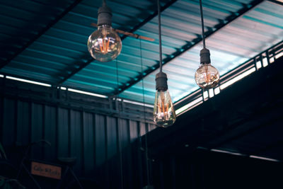 Low angle view of illuminated light bulbs hanging from ceiling