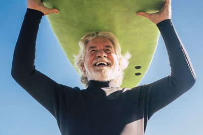 Low angle view of man with arms raised standing against white background