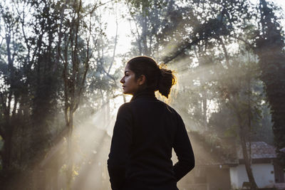 Side view of young man looking away in forest