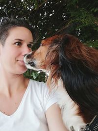 Woman with dog against trees